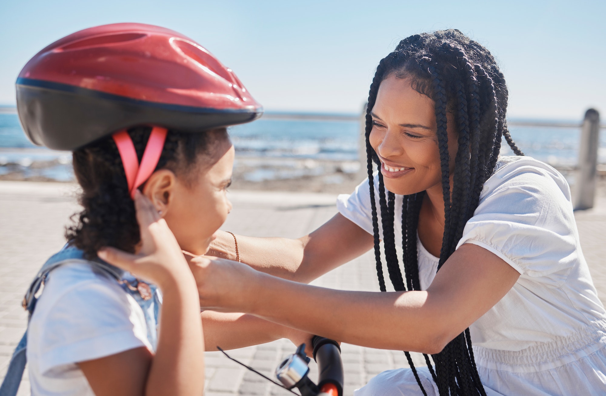 Mother, child or bike helmet help by beach, city ocean or sea in riding safety, learning security o